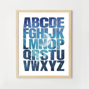 May include: A white background with a blue and white alphabet print. The letters are outlined in black and the background is a watercolor design of a night sky with stars and a crescent moon.