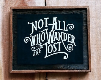 May include: A black wooden framed sign with white lettering that reads "Not all who wander are lost".