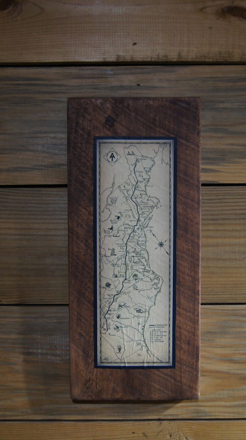 Op de afbeelding: Een ingelijste kaart van de Appalachian Trail, gedrukt op vintage papier met een bruine houten lijst.