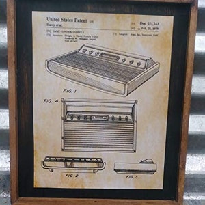 May include: A framed black and white patent drawing of a game console. The drawing shows the console from different angles. The patent number is Des. 251,143 and the date is Dec. 26, 1979.