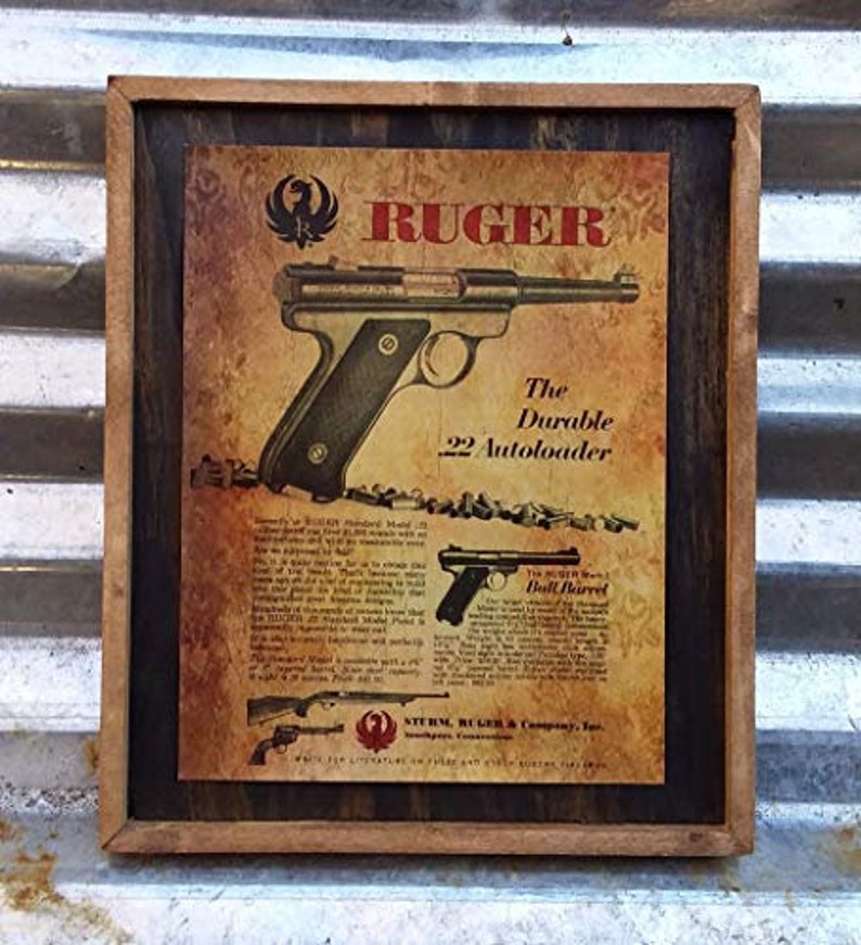 May include: Vintage framed advertisement for Ruger firearms. The print features a detailed illustration of a .22 Autoloader pistol, with additional images of other models. The text includes the Ruger logo and the phrase "The Durable 22 Autoloader."