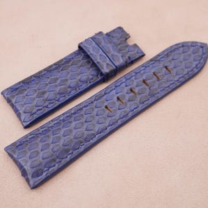 Puede incluir: Un par de correas de reloj de cuero azul con un patrón texturizado de piel de serpiente.