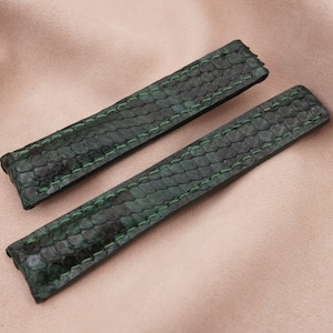 May include: Two dark green leather watch straps with a textured pattern and green stitching.