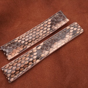 Puede incluir: Dos correas de reloj de cuero marrón claro con un patrón de piel de serpiente.