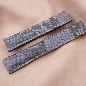 Puede incluir: Dos correas de reloj grises y azules con un patrón texturizado de piel de serpiente.