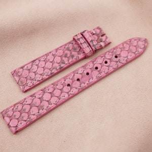 May include: Two pink watch straps made of patterned leather. The straps have a textured surface and are stitched together with white thread.