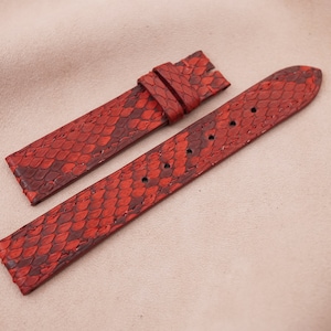 May include: Red leather watch strap with a snakeskin pattern.