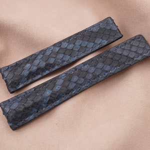 May include: Two dark blue watch straps made of textured leather with a snake skin pattern.