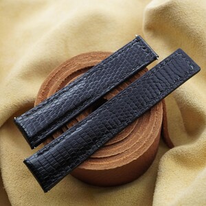 May include: A pair of black watch straps featuring a textured lizard-skin pattern. The straps are rectangular with straight edges, finished with tonal stitching along the borders and small metal spring bars visible at the attachment points.