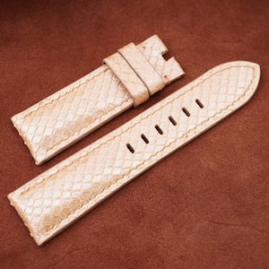 May include: A white leather watch strap with a textured pattern. The strap is made of genuine leather and has a classic design.