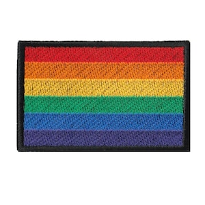 Op de afbeelding: Een regenboog-pride-vlagpatch met zes horizontale strepen in de kleuren rood, oranje, geel, groen, blauw en paars. De patch is omgeven door een zwarte rand.