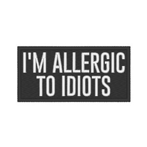 May include: A rectangular black embroidered patch with white text that reads "I'M ALLERGIC TO IDIOTS". The patch has a textured appearance, with the white text standing out against the dark background.