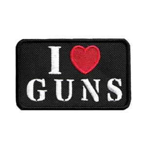 May include: Black embroidered patch with white text that reads "I love GUNS" and a red heart.