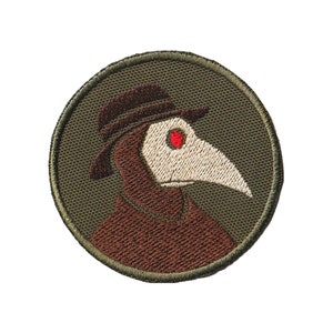 May include: A round, green embroidered patch featuring a brown plague doctor wearing a hat and a long, white beak. The doctor's eye is red.