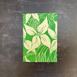 Puede incluir: Una tarjeta verde con un diseño floral blanco. Las flores son estilizadas y tienen un aspecto simple y elegante.