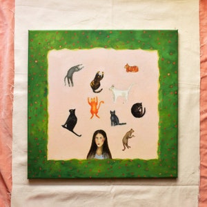 May include: A square canvas painting depicting a woman and several cat illustrations. The artwork has a pink background with a green border decorated with red dots. The cats are in different poses and colours, including black, white, orange, and grey.