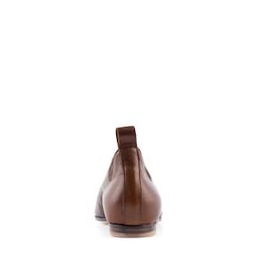 May include: A pair of brown leather slip-on shoes with a rounded toe and a low heel.