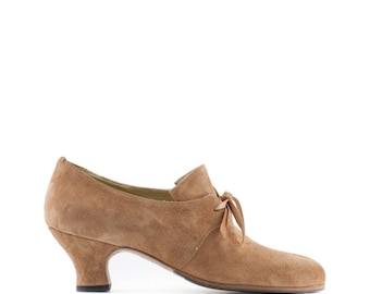 May include: A pair of brown suede heeled shoes with a lace-up detail at the ankle.