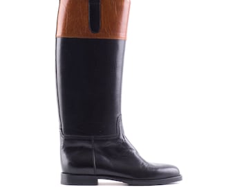 May include: Black leather riding boots with a brown leather top and a pull tab.