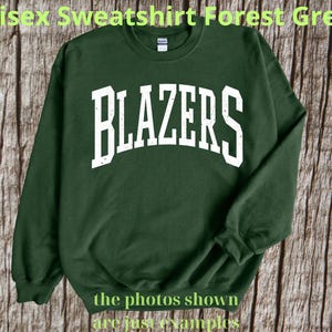 Puede incluir: Sudadera verde bosque con la palabra "BLAZERS" en letras blancas grandes y desgastadas en el pecho. La sudadera tiene cuello redondo y mangas largas. El texto "the photos shown are just examples" está en la parte inferior.