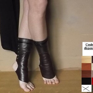 May include: A pair of black leather ankle boots with laces. The boots are worn on a person's legs with fishnet stockings. The text "Couleurs disponibles" is visible in the image.