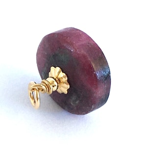 Op de afbeelding: Een roze en groene edelsteen hanger met een gouden beugel. De edelsteen is rond en heeft een glad oppervlak.