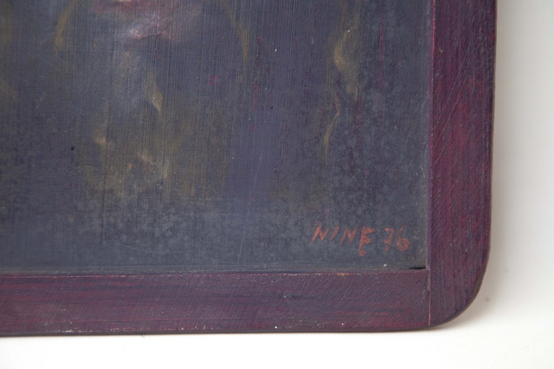 May include: A close-up of a dark gray chalkboard with a red wooden frame. The chalkboard has a faint image of a person's face and the text "NINE 76" written in red.