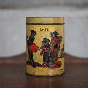 Peut inclure: Une boîte cylindrique vintage avec un fond jaune et des illustrations de personnages en tenue japonaise traditionnelle. Le mot "CAFE" est imprimé sur le devant. La boîte est probablement utilisée pour stocker du café ou du thé.