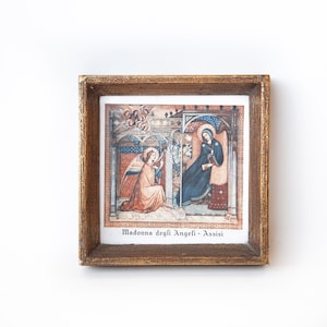 Peut inclure: Une estampe encadrée d'une peinture religieuse représentant la Madone et un ange. La peinture est dans un cadre doré et porte le texte "Madonna degli Angeli - Assisi" en bas.