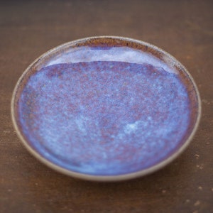 Peut inclure: Un petit plat rond en céramique avec un glaçage bleu et violet. Le plat a un aspect moucheté et est parfait pour servir de petites collations ou pour ranger des bijoux.