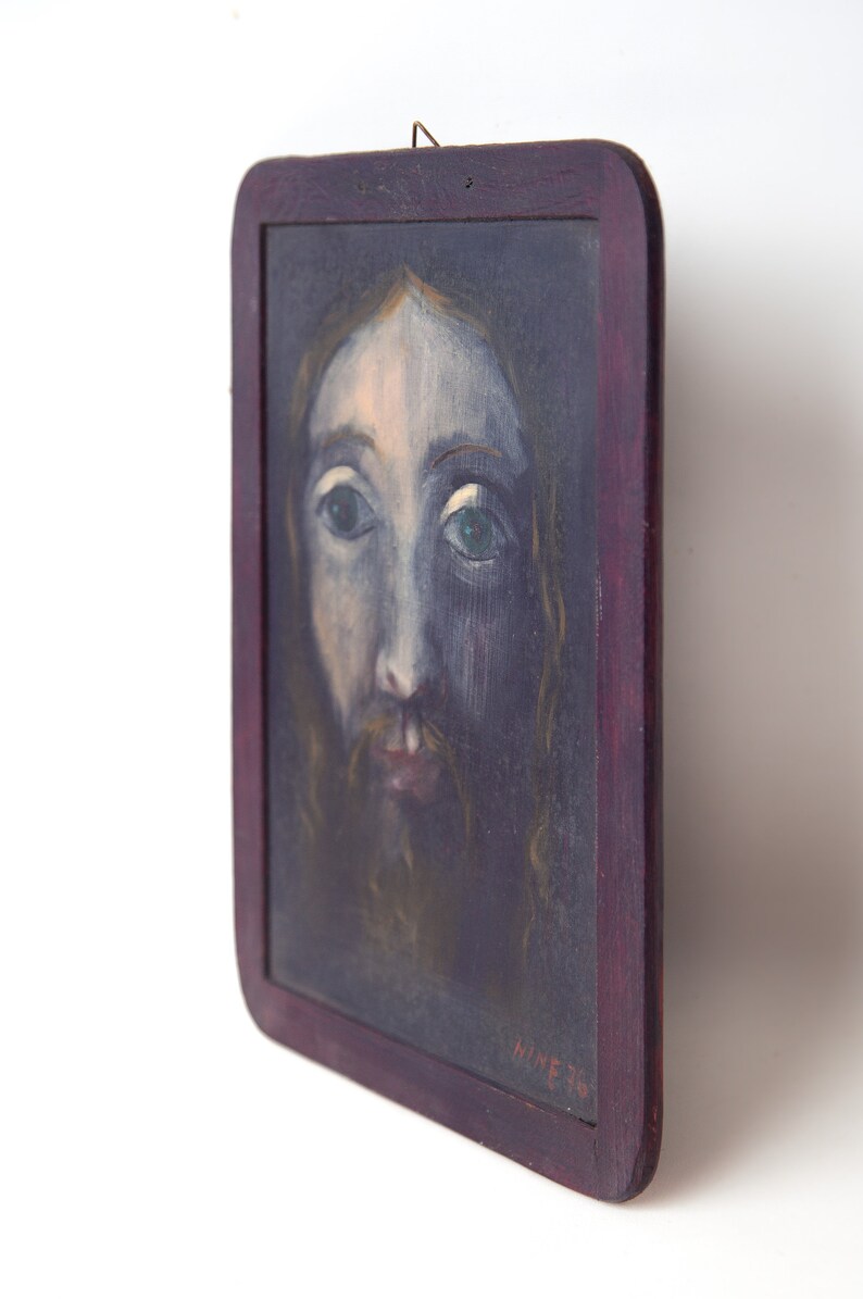 May include: A framed painting of a man's face with a beard and long hair. The painting is done in a dark blue and brown color scheme. The frame is dark wood with a red stain. The painting is signed "HINE 76" in the lower right corner.