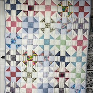 May include: A patchwork quilt with a star pattern. The quilt is made from a variety of fabrics in different colors and patterns, including blue, green, red, and white.