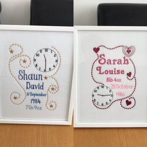 May include: Two framed embroidered birth announcement artworks. One features the name "Shaun David", birthdate, and weight, with a clock design. The other displays "Sarah Louise", birth details, and a clock design, all in a white frame.