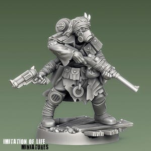 Könnte beinhalten: Graue Miniaturfigur einer postapokalyptischen Figur, die eine Gasmaske, einen bandagierten Kopf und Kleidung im Militärstil trägt. Die Figur hält ein Gewehr und einen Revolver. Auf dem Sockel der Figur steht der Text "IMITATION OF LIFE MINIATURES".