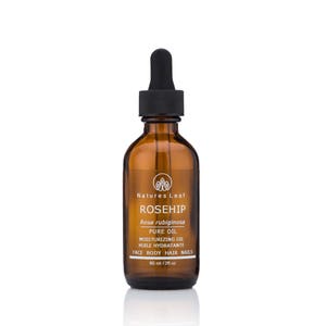 May include: A brown glass bottle with a dropper top containing rosehip oil. The bottle is labeled "Natures Leaf Rosehip Rosa rubiginosa Pure Oil Moisturizing Oil Huile Hydratante Face Body Hair Nails 60 ml / 2 fl oz."
