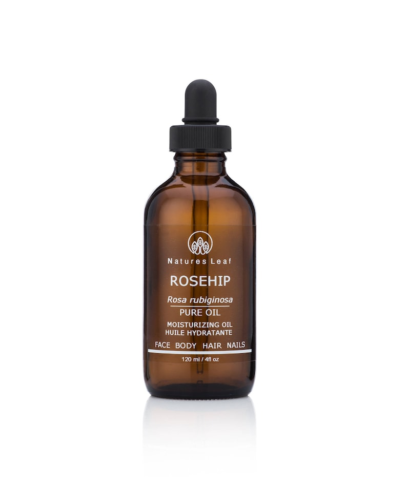 May include: A brown glass bottle with a black dropper top, labeled "Rosehip Pure Oil" with the text "Rosa rubiginosa" and "Moisturizing Oil, Huile Hydratante, Face Body Hair Nails, 120 ml / 4 fl oz".