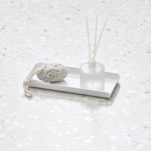 May include: A white rectangular tray with a gray pumice stone and a clear glass bottle with diffuser sticks.