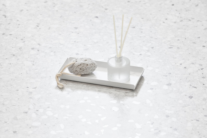 May include: A white rectangular tray with a gray pumice stone and a clear glass bottle with diffuser sticks.