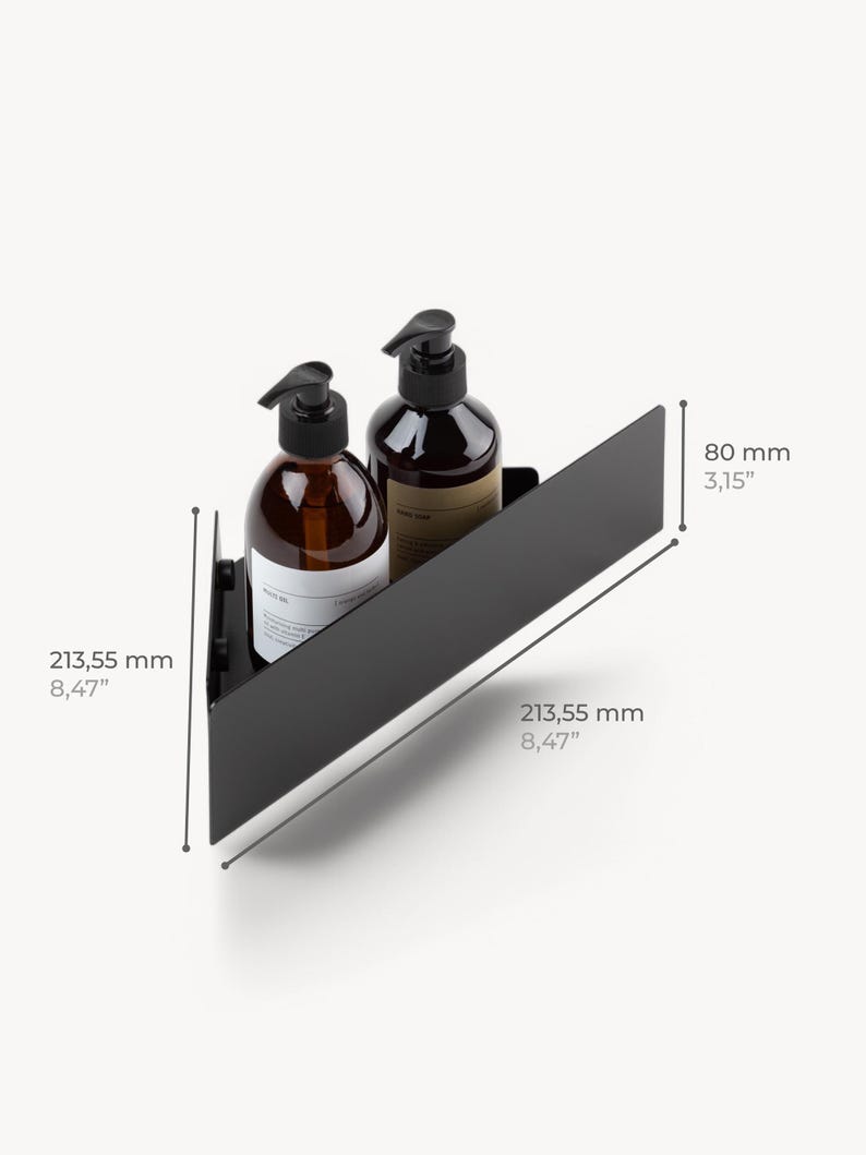 May include: A matte black triangular corner shelf holding two amber glass pump bottles. The shelf measures 8.47 inches along the two back sides and 3.15 inches in height. The design features a solid metal construction with a front-facing panel.