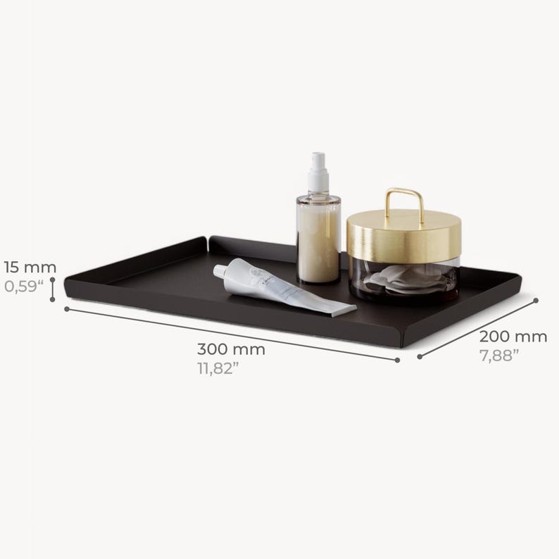 May include: Black metal tray with rounded edges, measuring 11.82 inches by 7.88 inches, with a gold lidded jar, a tube of cream, and a bottle of spray.