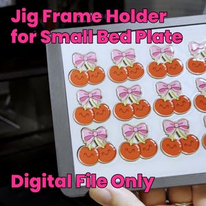 Può includere: Un supporto per telaio a dima grigio per una piccola piastra da letto con una griglia di grafiche a ciliegia stampate. Ogni coppia di ciliegie è arancione con una faccia sorridente e un fiocco rosa. Il testo Jig Frame Holder for Small Bed Plate e Digital File Only è visibile.