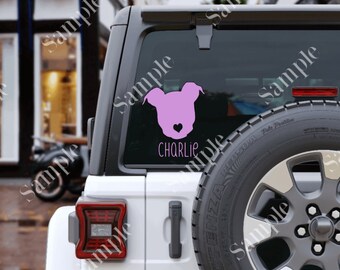 May include: Pink dog silhouette decal with the name Charlie on a white car window.