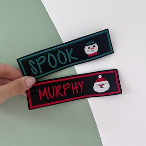 May include: Two embroidered patches with black backgrounds. One patch reads "SPOOK" in green with a snowman graphic. The other patch reads "MURPHY" in red with a Santa Claus graphic. Both patches have a rectangular shape.