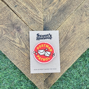 May include: Red and white iron-on merit badge for dogs. The badge features a red circle with the words "Postman Patrol" and a cartoon image of two envelopes. The text "Scout's Honour" is printed on the card.