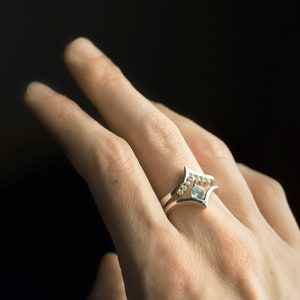 Sterling silver cubic zirconia enhancer chevron band and sterling silver moonstone ring on hand. Moonstone and CZ stacking rings