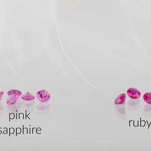 May include: Pink sapphires and rubies, both in a round cut, are displayed on a white surface. The sapphires are on the left and the rubies are on the right. The text "pink sapphire" is below the sapphires and the text "ruby" is below the rubies.