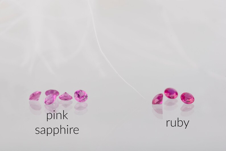 May include: Pink sapphires and rubies, both in a round cut, are displayed on a white surface. The sapphires are on the left and the rubies are on the right. The text "pink sapphire" is below the sapphires and the text "ruby" is below the rubies.