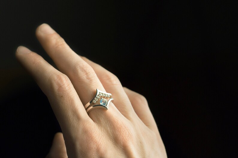 Sterling silver cubic zirconia enhancer chevron band and sterling silver moonstone ring on hand. Moonstone and CZ stacking rings