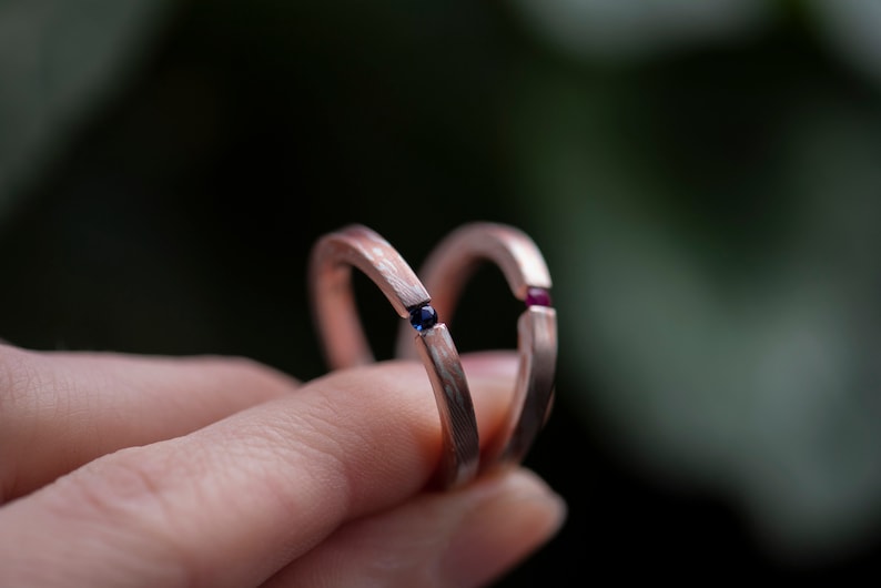 Two mokume gane sterling silver and copper tension engagement rings - one with natural blue sapphire and one with natural deep pink ruby