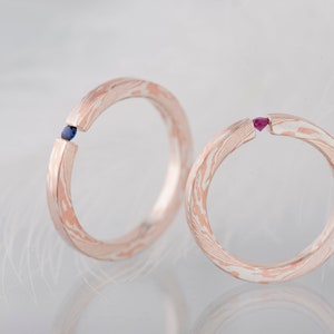 Two mokume gane sterling silver and copper tension engagement rings - one with natural blue sapphire and one with natural deep pink ruby
